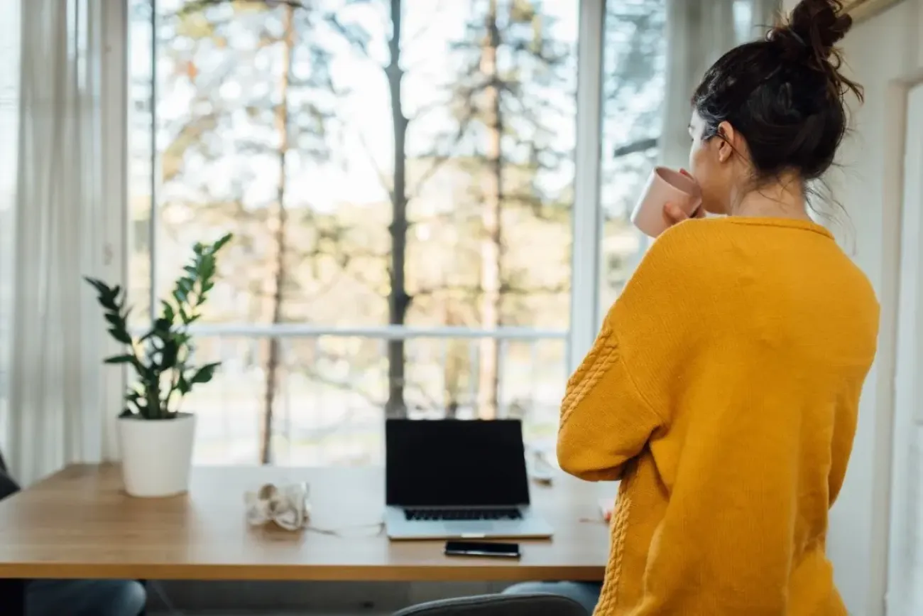 Kvinna som står och tittar ut genom ett fönster