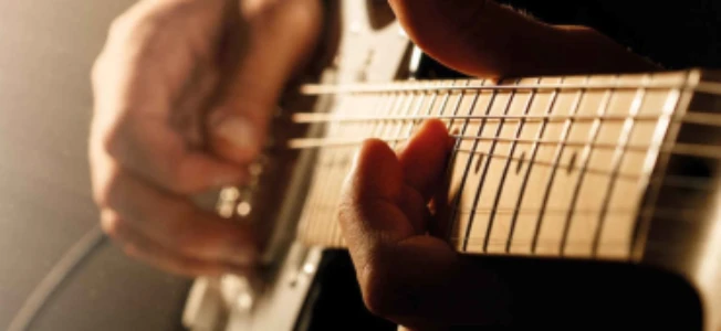 En person som spelar gitarr, lyssna på musik som veckans utmaning