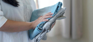 Kvinna håller i ihopvikta jeans när hon rensar hemma